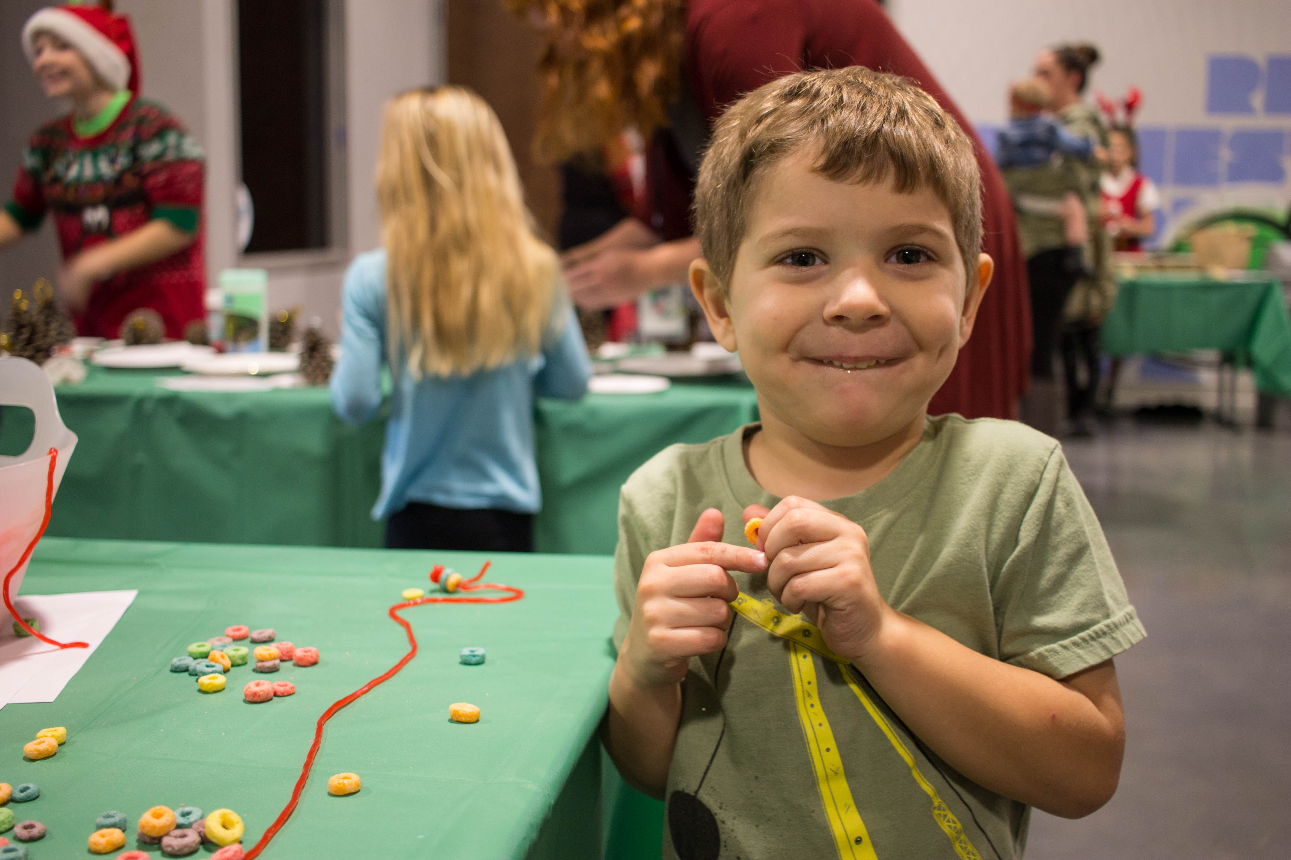 Johnny making a cereal necklace at the craft table during breakfast with Santa
