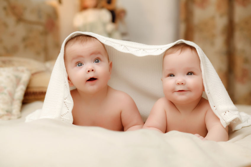 twin babies hiding under a blanket